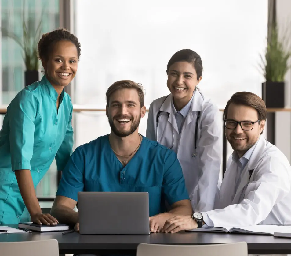 Smiling medical team around a laptop.